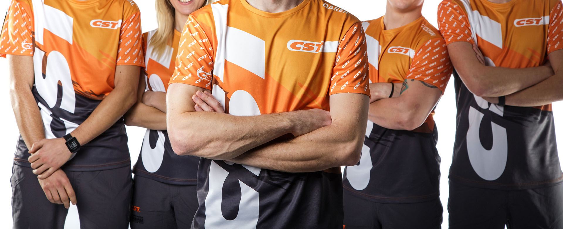 Five people in matching orange and graphite company shirts with arms crossed