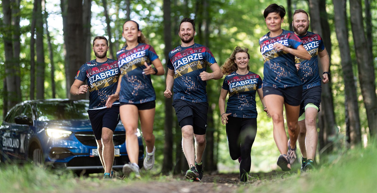 Six runners on a forest trail in matching Kanclerz Zabrze Half Marathon shirts