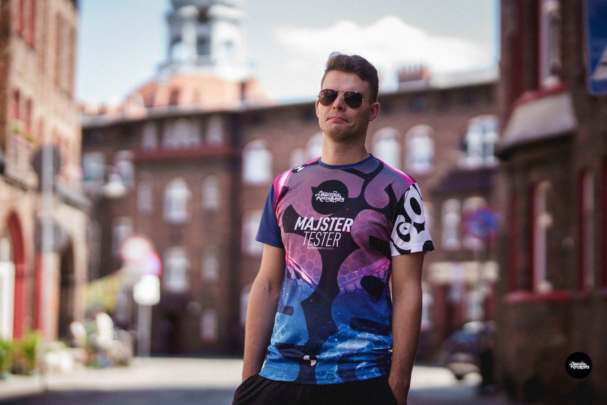 Man in a colourful sublimated running shirt on a street of red-brick buildings